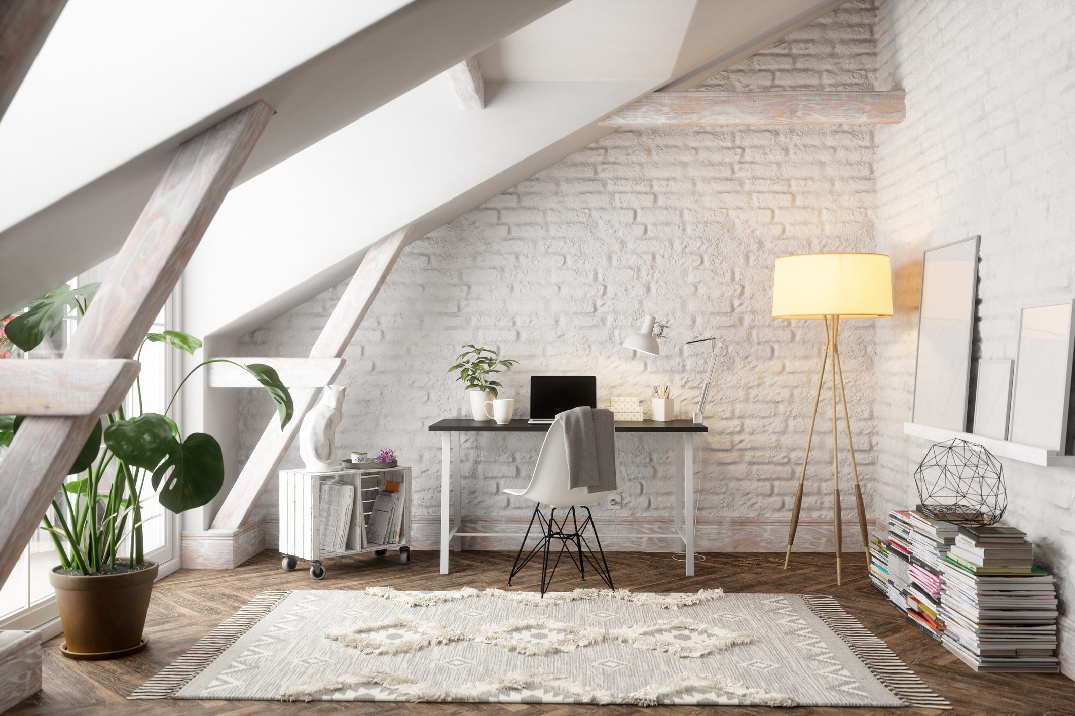 Desk with laptop and plant; chair draped with gray fabric; modern attic room with slanted ceiling, white brick walls, large plant, and floor lamp.