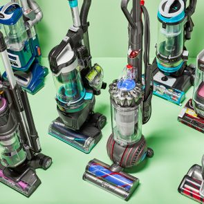 Various vacuum cleaners stand displayed in a green setting, showcasing different models and designs.