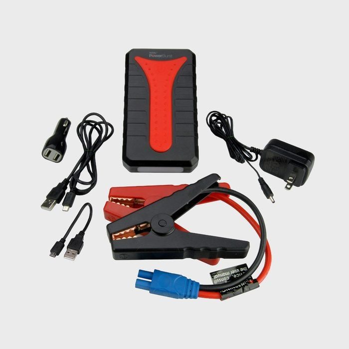 Portable jump starter with red-black clamps, USB cables, car charger, and power adapter arranged on a light gray surface.