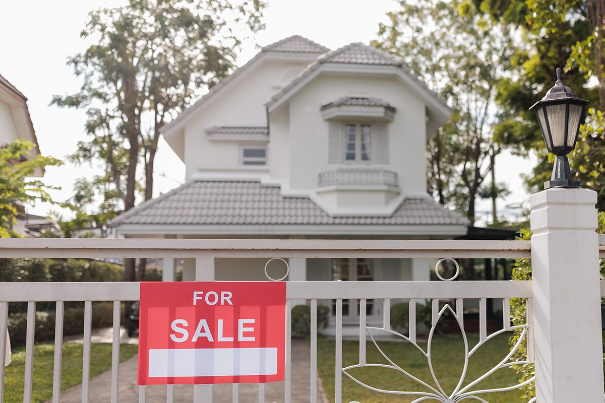 For sale real estate sign in front of house