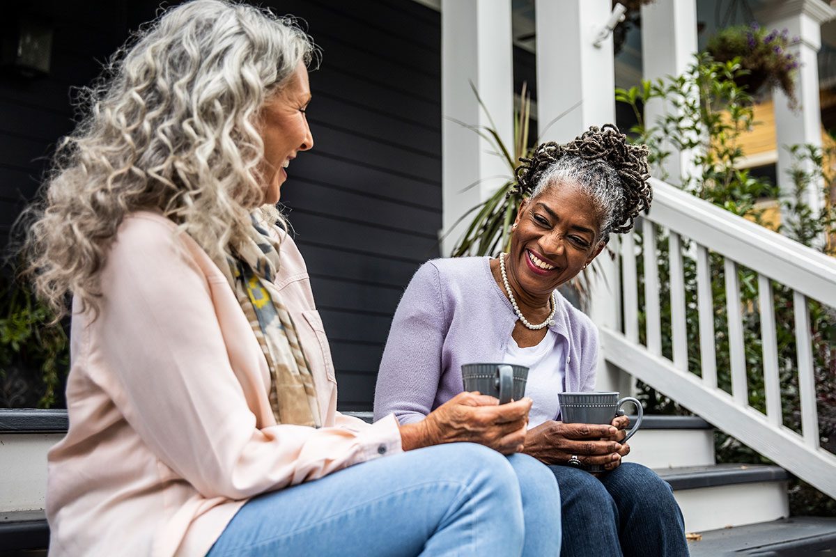 Senior women having coffee in front of suburban home